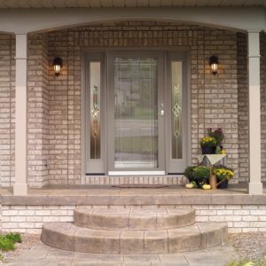 A home with brick exterior has a beautiful entryway with a glass storm door.