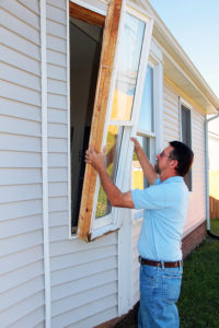 A window installer installing a window on a white home.