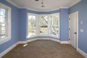 An interior view of white bow windows in a room painted light blue