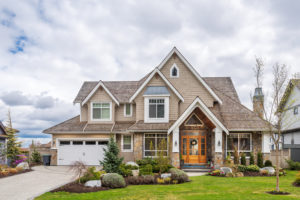 A beautiful two-story home with stone siding, and a well-manicured lawn.